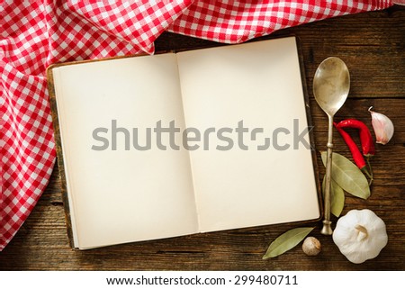 Open cookbook with kitchenware on checkered tablecloth