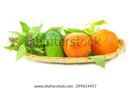 Basil tomato and cucumber in wicker basket on white background