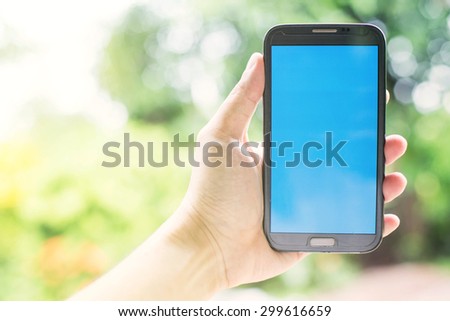 man hand holding smartphone against spring green background, smartphone with color background as social network application.