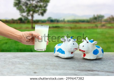 hand holding glass of milk on farm background.