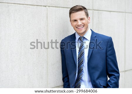 Image of a happy businessman leaning against a wall