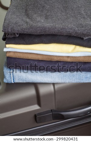 Stack of shirt and jean with travel suitcase