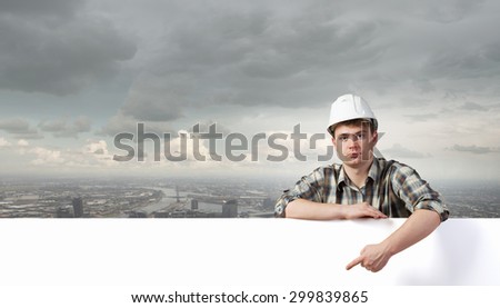 Young builder man with white blank banner. Place for text