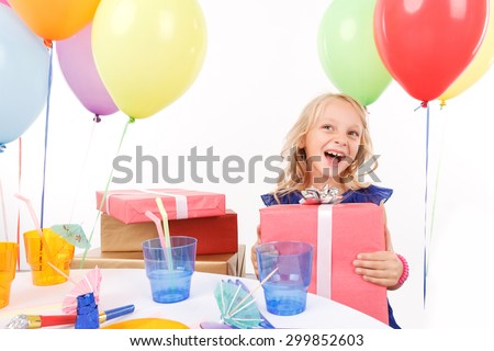 My birthday present. Smiling upbeat girl sitting at the table and holding bright 
