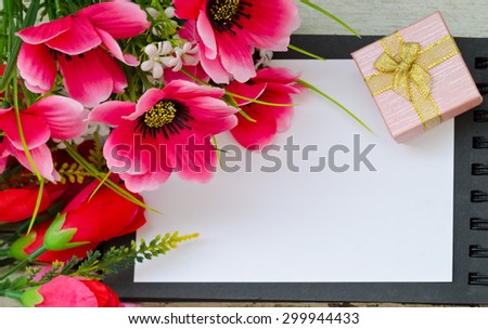 Bouquet of colorful flowers and gift box on open book