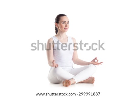 Sporty beautiful young woman practicing yoga, Sitting in Easy (Decent, Pleasant Pose), Sukhasana, asana for meditation, pranayama, breathing, studio full length isolated shot, three-quarters view