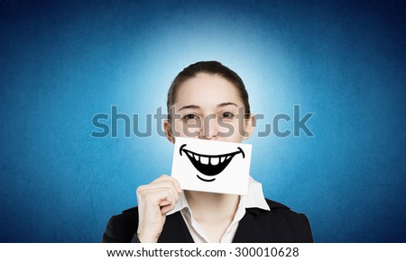 Pretty young girl holding white card with drawn smile