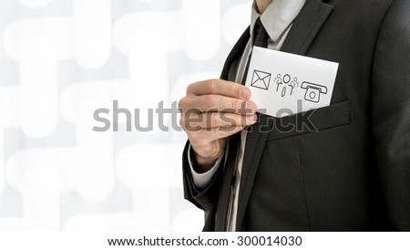 Personal business consultant  removing a business card with communication and people icons - phone, email and contact center icon - from the inner pocket of his jacket, close up view.