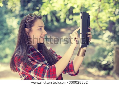 Beautiful young woman taking picture of herself, selfie with mobile pc. Filtered image.