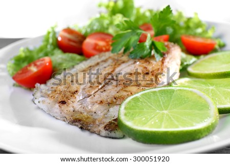 Dish of fish fillet with salad and lime on plate close up
