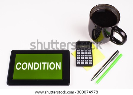 Business Term / Business Phrase on Tablet PC - Cup of coffee, Pens, Calculator and a green/yellow note pad on a White surface - White Word(s) on a green background - Condition