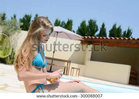 beautiful young woman applying sunscreen protection tan in summertime by the pool