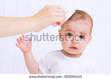 Mother is combing beautiful baby`s hair