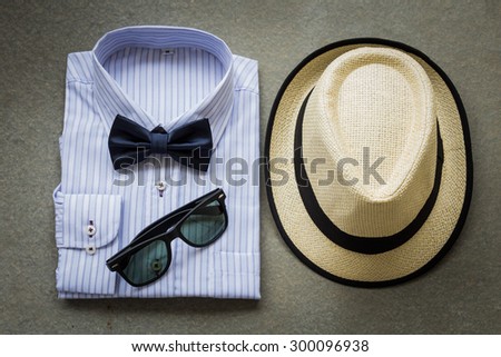 Men's casual, shirt with bowtie, hat and sunglasses on wooden background