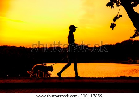silhouette of girl walking with her puppy Royalty-Free Stock Photo #300117659