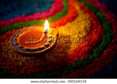 Traditional diya lamp lit on colorful rangoli Royalty-Free Stock Photo #300168158