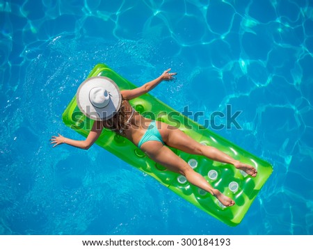 Top view of a  girl in the swimming pool on a lilo