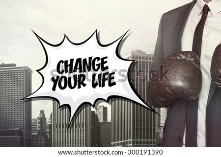 Change your life text with businessman wearing boxing gloves on cityscape background