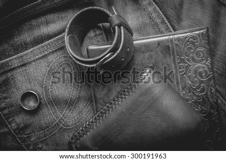 still life photography : Black and white leather wallet, Leather wristbands, silver ring and adventure hat on jeans background,  men casual concept, vintage and retro style.