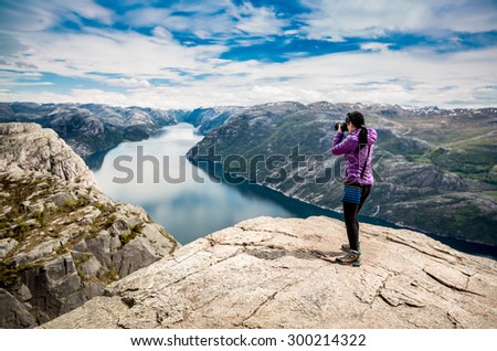 Nature photographer tourist with camera shoots while standing on top of the mountain. Beautiful Nature Norway Preikestolen or Prekestolen.