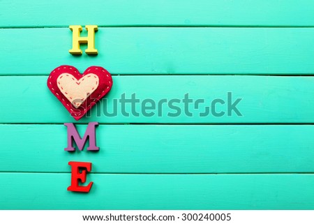 Decorative letters forming word HOME with heart on wooden background