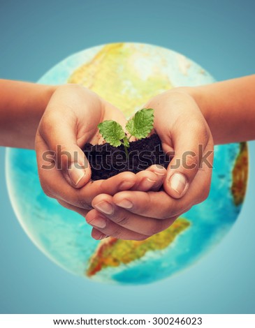 people, ecology, environment, agriculture and food concept - close up of woman hand with green sprout over earth globe over blue background