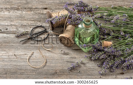 Lavender oil with fresh flowers and scissors on wooden background. Vintage style colored picture. Selective focus