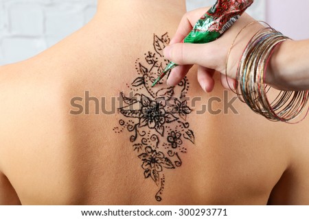Process of applying Mehendi on female back, close up