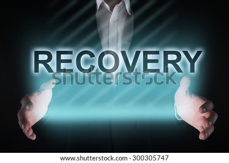 Glowing text "recovery" in the hands of a businessman. Business concept.