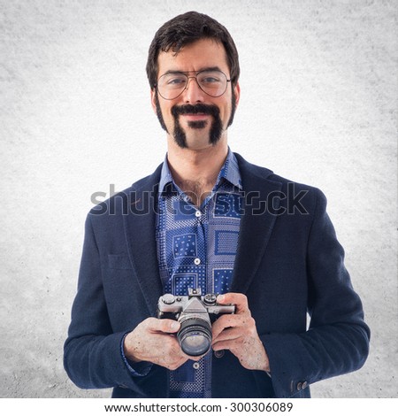 Vintage young man with camera over grey background