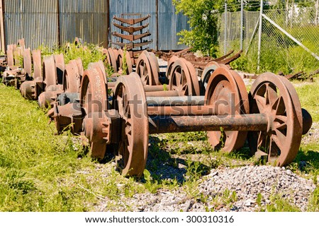 A stockpile of old, rusty and abandoned train wheels lying in the grass close to train service depot.