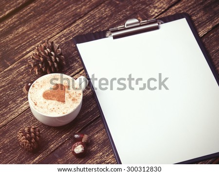 Cup of coffee and tablet on wooden table.