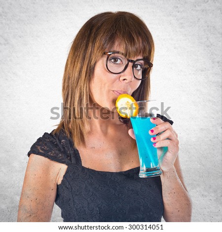 Woman drinking a cocktail over grey background