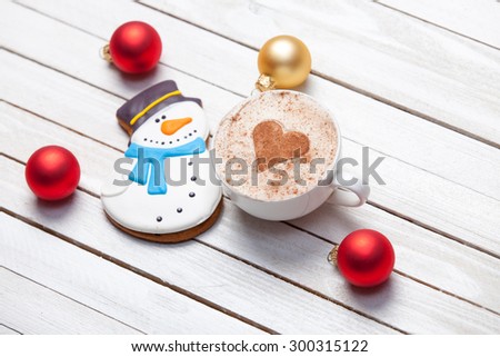 Cup of coffee with heart shape and christmas gingerbread on white wooden background.