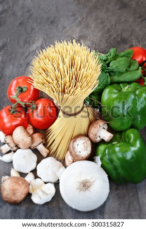 Above shot of spaghetti with ingredients of basil leaves, garlic, white onions, mushrooms, peppers and fresh tomatoes with extreme shallow depth of field.