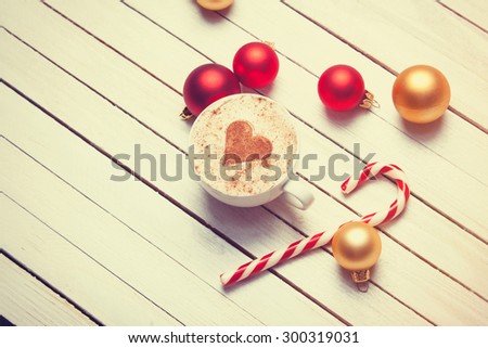 Cup of coffee with heart shape and christmas candy on white wooden background.