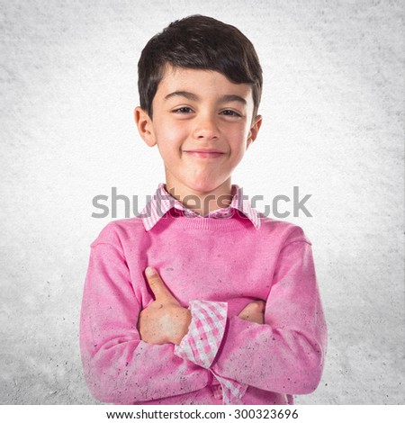 Brunette kid with his arms crossed over grey background
