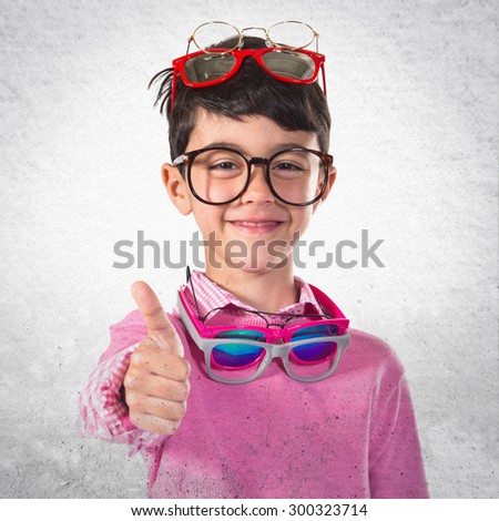 Happy boy with many glasses over grey background
