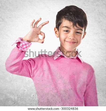 Child making Ok sign over grey background