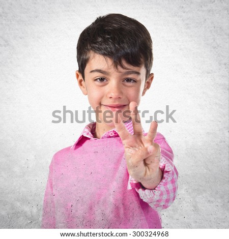 Child counting three over grey background