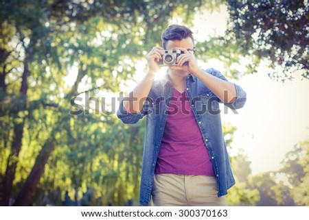 Handsome hipster using vintage camera on a sunny day