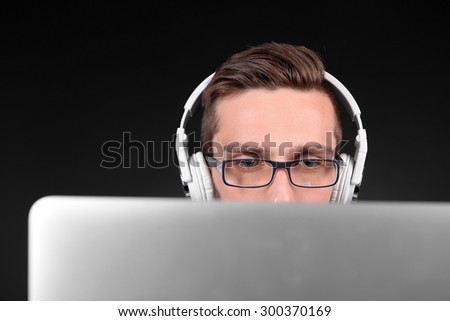 Handsome young man with laptop on grey background
