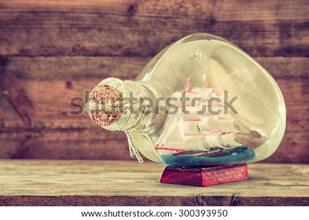 image of decorative boat in the bottle on wooden table. nautical concept. retro filtered image
