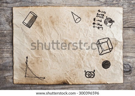 Piece of old rumpled paper with mathematics doodles on wooden floor background