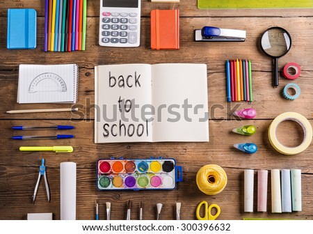 Desk with stationary and with Back to school sign. Studio shot on wooden background. 
