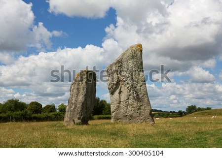 Pair of Standing stones that form part of the ancient megalith circle in the village of Avebury in Wiltshire.
Neolithic bluestones with a curved white cloud in blue sky Royalty-Free Stock Photo #300405104