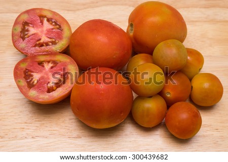 Fresh tomatoes and cherry tomato on wood background