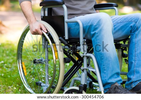 Detail of a man using a wheelchair in a park Royalty-Free Stock Photo #300454706