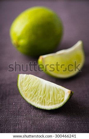 Fresh juicy limes on dark canvas background close up