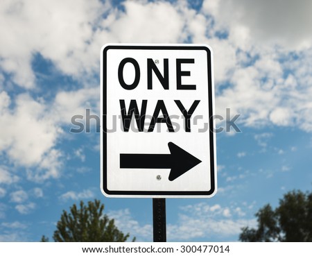 A one way sign against a blue sky.